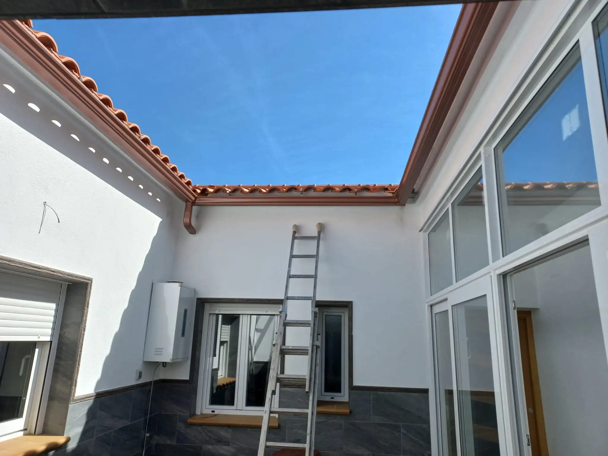 Canalón de aluminio en patio de Córdoba con tubo en pared
